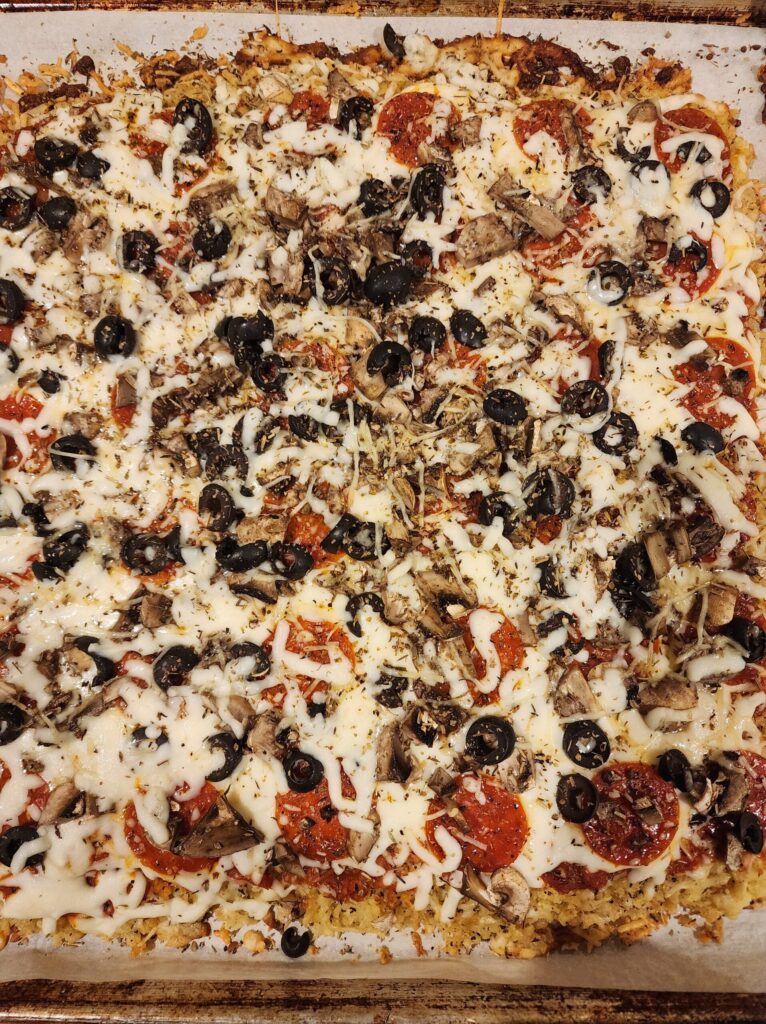 Baked tater tot pizza on a cookie sheet.